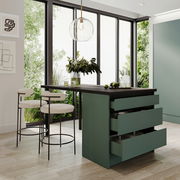 Moderne Kücheninsel mit grünen Schubladen und dunkler Arbeitsplatte, umgeben von hohen Fenstern mit Blick ins Grüne, aus seitlicher Perspektive.