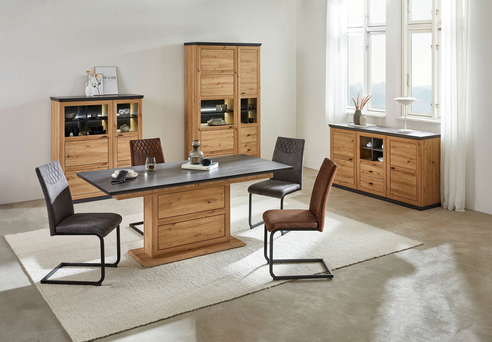 Hom´in Funktions-Esstisch BENTON Moderner Funktions-Esstisch aus Holz mit dunkler Tischplatte, umgeben von vier Stühlen in einem hellen Raum mit großen Fenstern, aus der Perspektive von vorne.