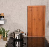 Rechteckige Schneide- und Abdeckplatte aus Holz, stehend auf einer Küchenarbeitsplatte neben einem Topf und Gewürzglas, aus frontaler Perspektive.