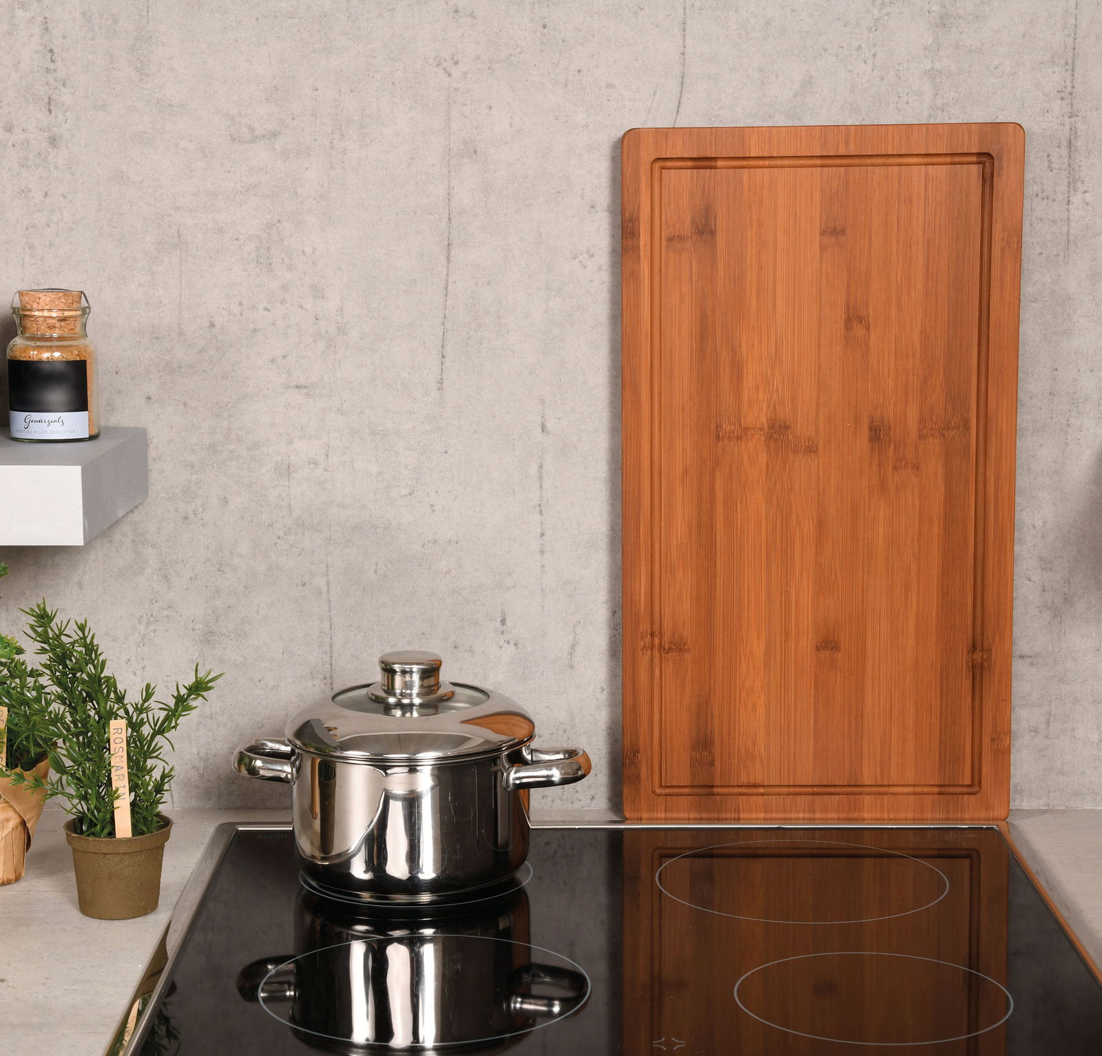 Rechteckige Schneide- und Abdeckplatte aus Holz, stehend auf einer Küchenarbeitsplatte neben einem Topf und Gewürzglas, aus frontaler Perspektive.