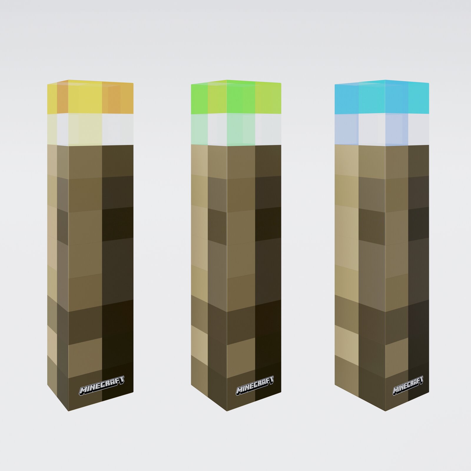 Drei hohe, quaderförmige Minecraft-Produktboxen mit pixeligem Braun-Muster und farbigen Deckeln (gelb, grün, blau) auf hellem Hintergrund, schräg von vorn in leichter Seitenansicht fotografiert.