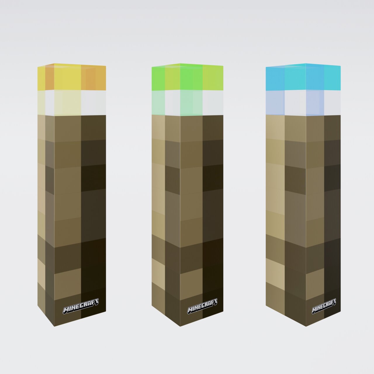 Drei hohe, quaderförmige Minecraft-Produktboxen mit pixeligem Braun-Muster und farbigen Deckeln (gelb, grün, blau) auf hellem Hintergrund, schräg von vorn in leichter Seitenansicht fotografiert.