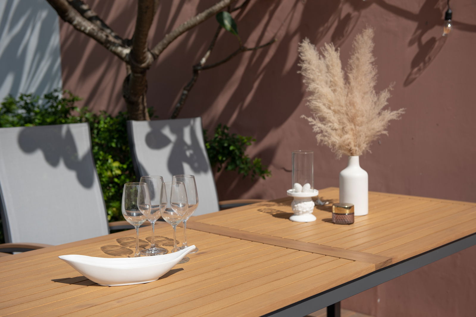 Gartentisch mit Holzoptik, dekoriert mit Gläsern, Vase und Kerzenhalter, seitliche Perspektive