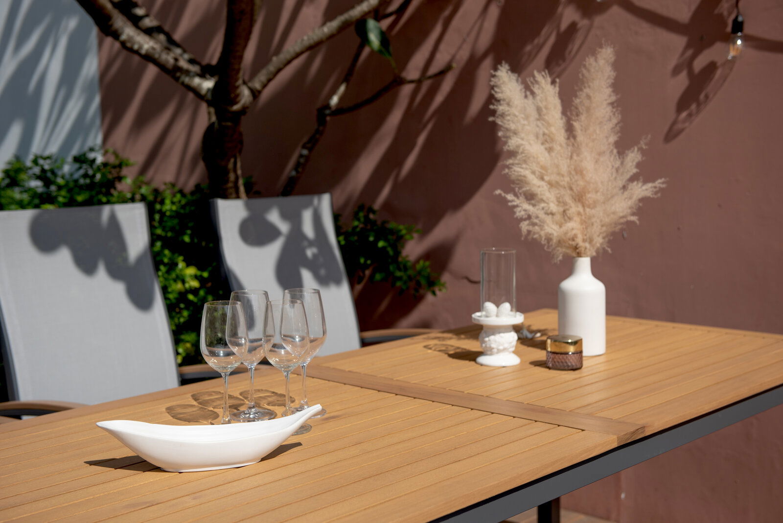 Gartentisch mit Holzoptik, dekoriert mit Gläsern, Vase und Kerzenhalter, seitliche Perspektive