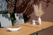 Gartentisch mit Holzoptik, dekoriert mit Gläsern, Vase und Kerzenhalter, seitliche Perspektive