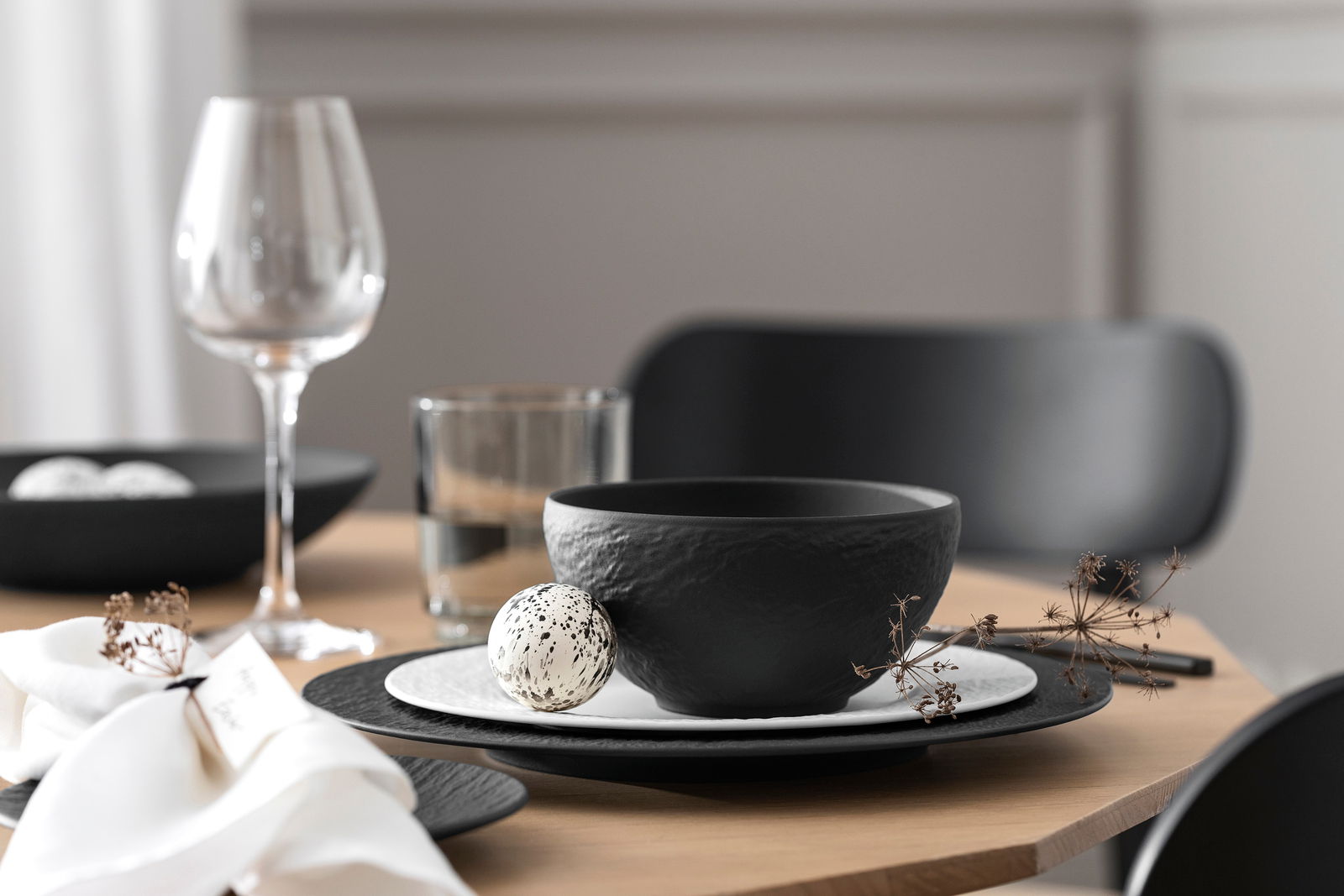 Villeroy & Boch Bowl MANUFACTURE ROCK Schwarze Müslischale aus der Manufacture-Serie, auf einem gedeckten Tisch mit einem Ei und einem Weinglas, seitliche Perspektive.
