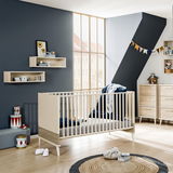 Modernes Babybett in einem stilvoll eingerichteten Kinderzimmer mit Blick auf die Seite des Bettes.