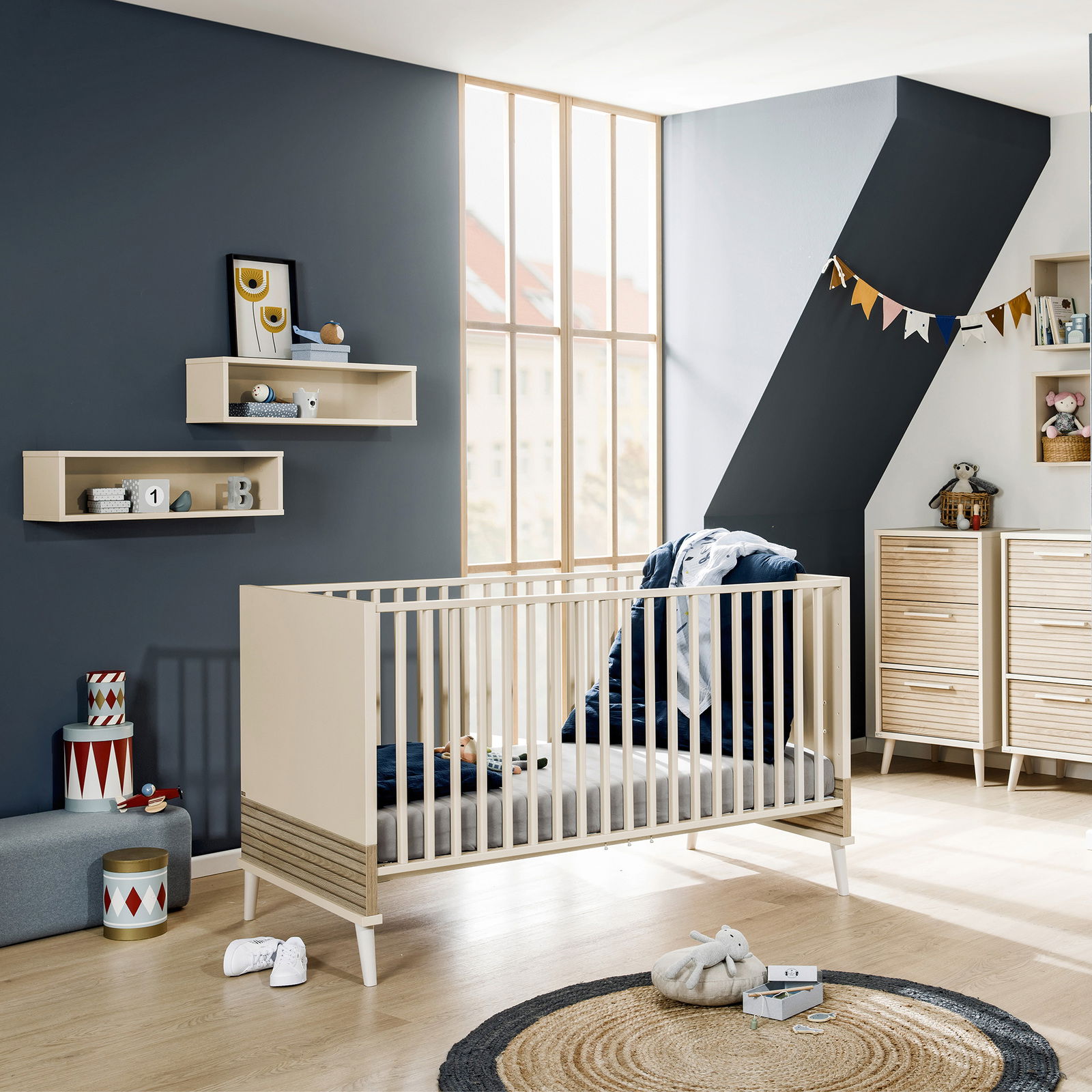 Modernes Babybett in einem stilvoll eingerichteten Kinderzimmer mit Blick auf die Seite des Bettes.