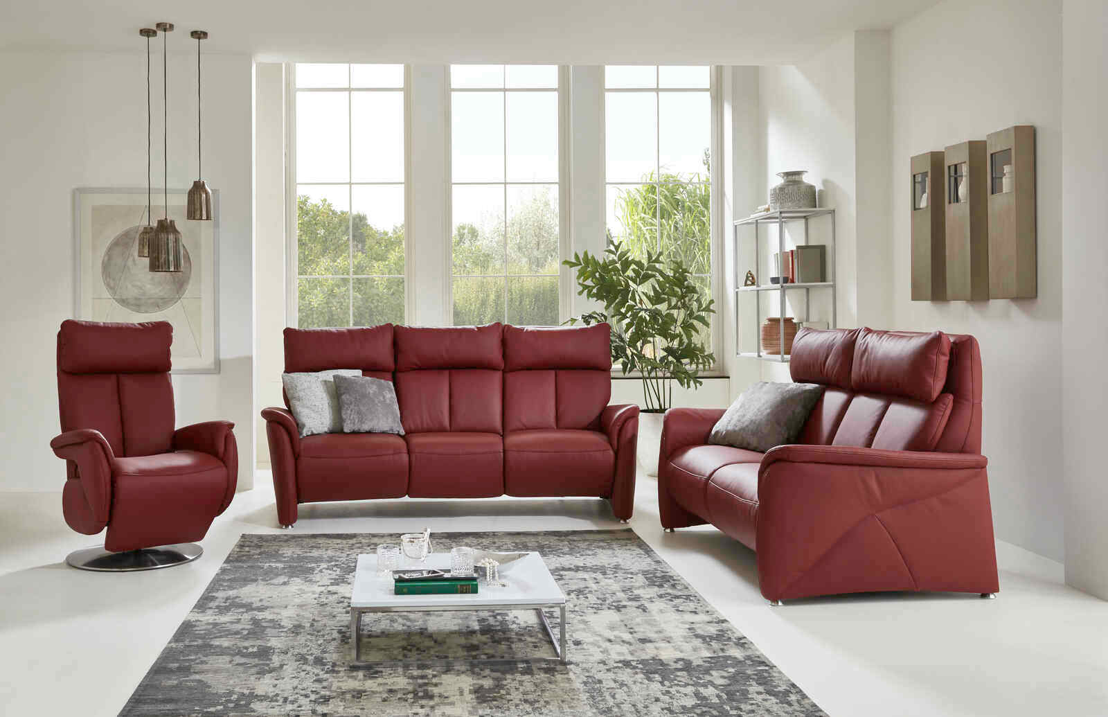 Wohnzimmeransicht mit einem roten Fernsehsessel und passendem Sofa-Set in einem modernen, hellen Raum mit großen Fenstern.