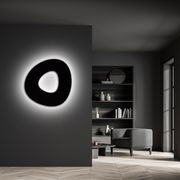 Moderne LED-Deckenleuchte in organischer Form, an einer dunklen Wand montiert, mit sanftem Umgebungslicht, seitliche Perspektive.