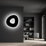 Moderne LED-Deckenleuchte in organischer Form, an einer dunklen Wand montiert, mit sanftem Umgebungslicht, seitliche Perspektive.