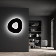 Moderne LED-Deckenleuchte in organischer Form, an einer dunklen Wand montiert, mit sanftem Umgebungslicht, seitliche Perspektive.