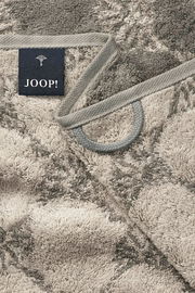 Nahaufnahme eines gemusterten Handtuchs mit grauen und beigen Tönen, Markenetikett 'JOOP!' sichtbar.