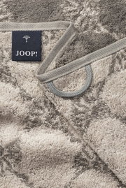 Nahaufnahme eines gemusterten Handtuchs mit grauen und beigen Tönen, Markenetikett 'JOOP!' sichtbar.