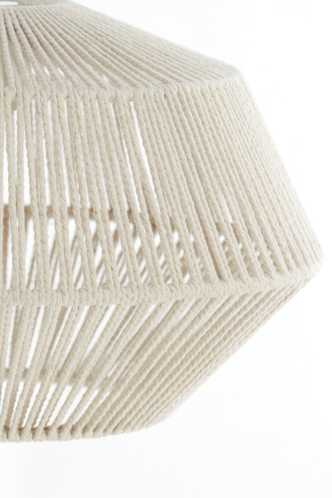 Detailopname vanuit zijaanzicht van een crèmekleurige lampenkap, opengewerkt met gevlochten koord in een geometrische vorm.