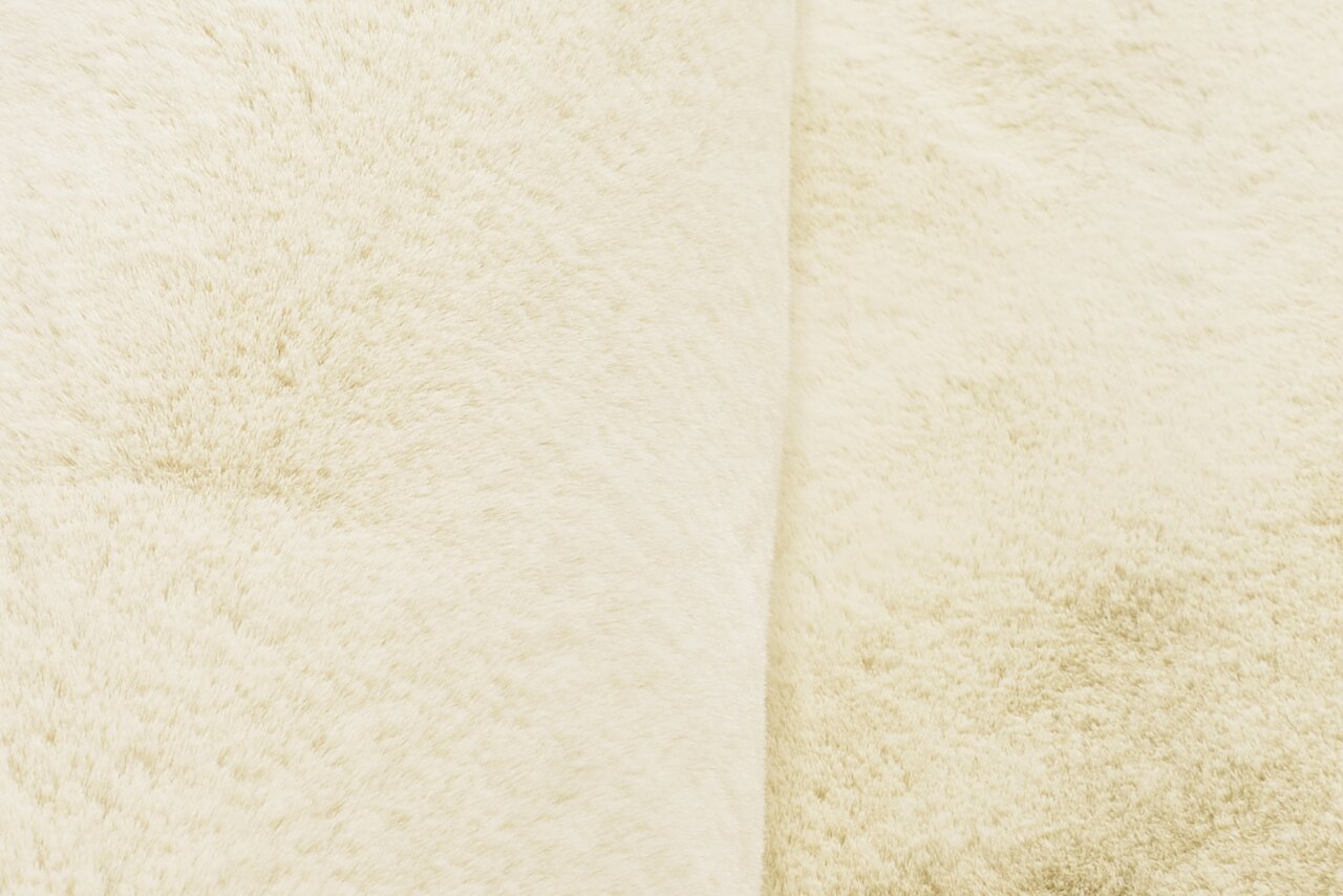 Nahaufnahme eines cremefarbenen Fellteppichs mit weicher Textur