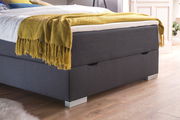 Boxbett in grauem Stoffbezug mit gelber Decke, seitliche Perspektive