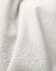 Nahaufnahme einer Bettwäsche mit dezentem Fischgrätenmuster in Beige.