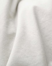 Nahaufnahme einer Bettwäsche mit dezentem Fischgrätenmuster in Beige.