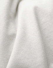 Close-up van beddengoed met een subtiel visgraatpatroon in beige.