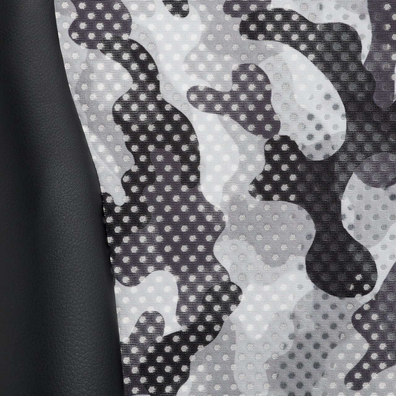 Nahaufnahme eines Gamingstuhl-Materials mit grauem Tarnmuster und schwarzem Kunstleder, seitliche Perspektive