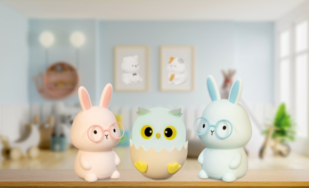 Zwei Hasen-Nachtlichter mit Brillen und ein Eulen-Nachtlicht in einem Ei, frontal auf einem Regal in einem Kinderzimmer platziert.