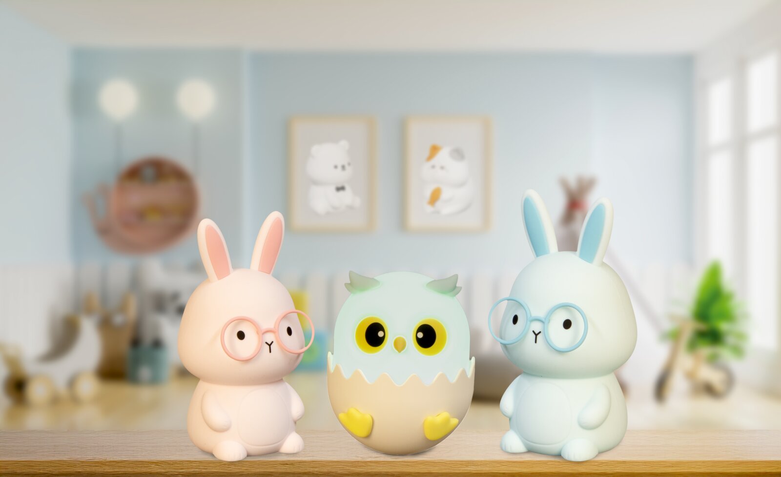 Zwei Hasen-Nachtlichter mit Brillen und ein Eulen-Nachtlicht in einem Ei, frontal auf einem Regal in einem Kinderzimmer platziert.