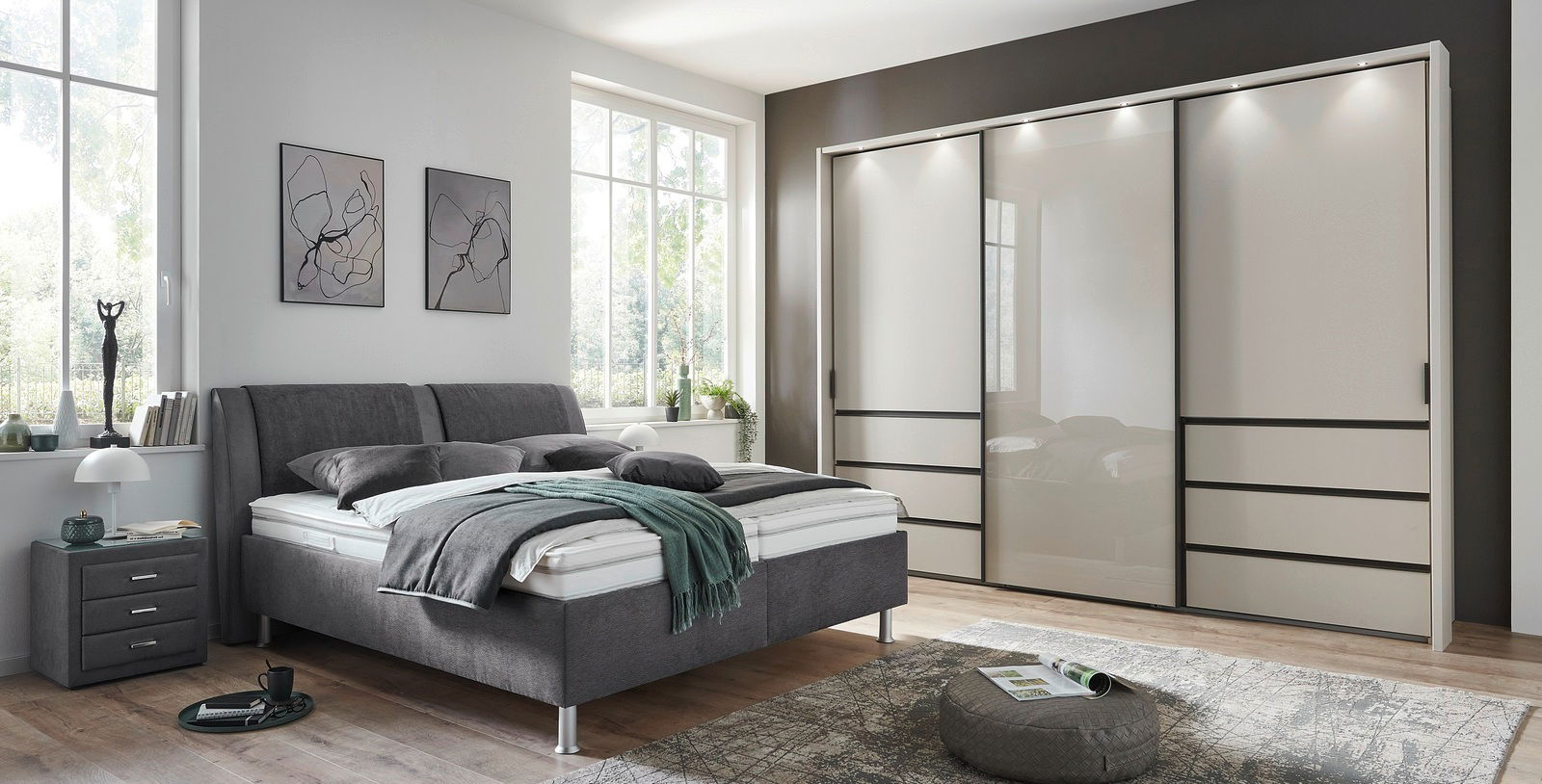 Modernes Polsterbett in einem stilvollen Schlafzimmer, seitliche Perspektive mit grauem Kopfteil und passendem Nachttisch.