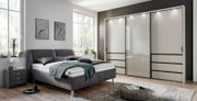 Modernes Polsterbett in einem stilvollen Schlafzimmer, seitliche Perspektive mit grauem Kopfteil und passendem Nachttisch.