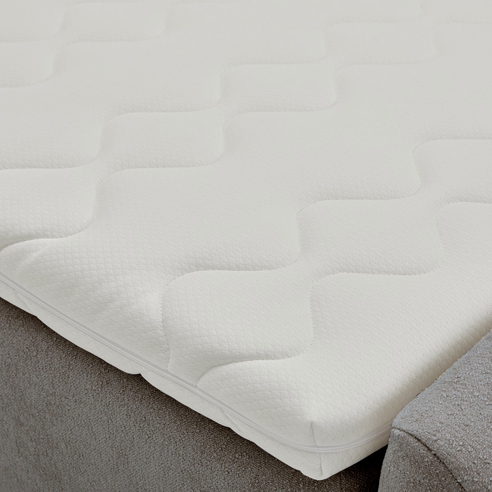 Nahaufnahme eines Boxbetts mit weißem, strukturiertem Matratzenbezug in Wellenmuster.