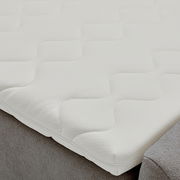 Nahaufnahme eines Boxbetts mit weißem, strukturiertem Matratzenbezug in Wellenmuster.