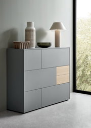 Modernes Highboard in Grau mit Holzakzent, seitliche Perspektive, dekoriert mit Vasen und Lampe.