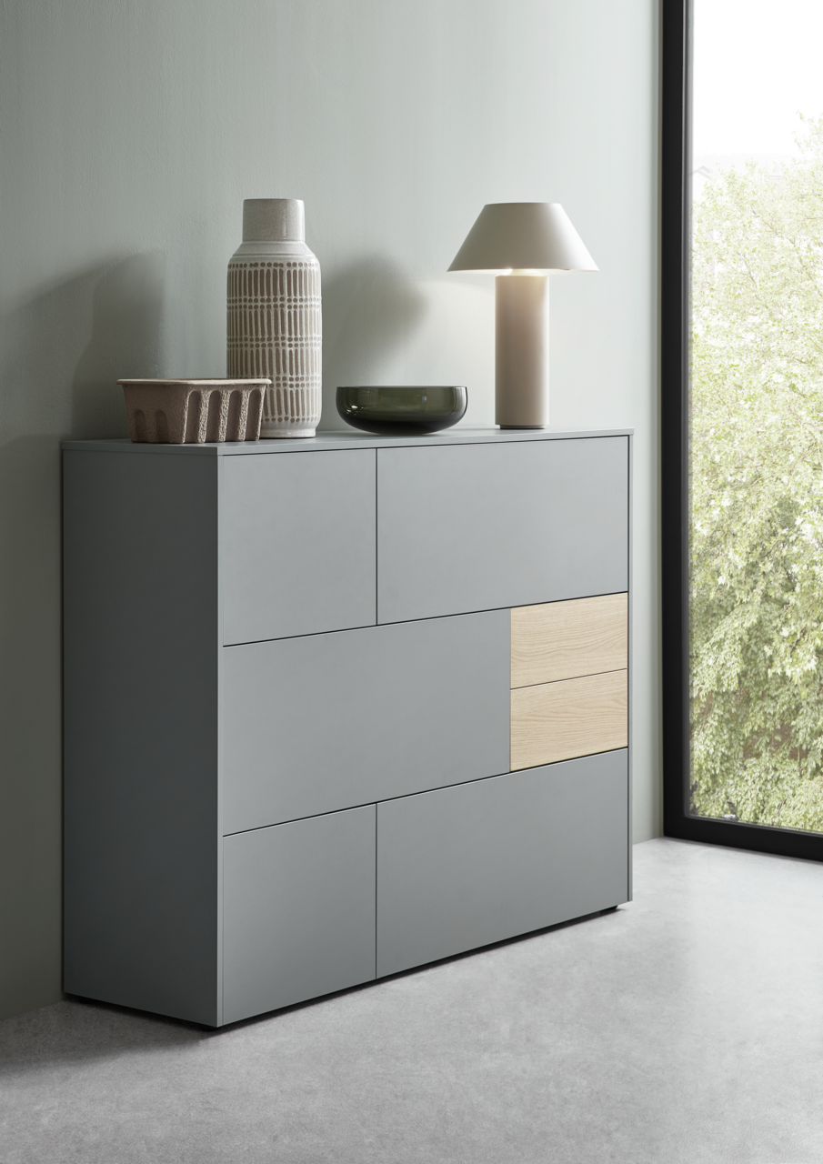 Modernes Highboard in Grau mit Holzakzent, seitliche Perspektive, dekoriert mit Vasen und Lampe.