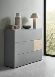 Modernes Highboard in Grau mit Holzakzent, seitliche Perspektive, dekoriert mit Vasen und Lampe.