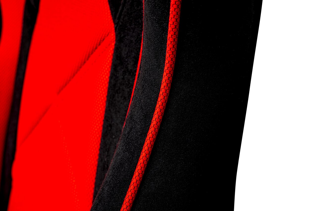 Nahaufnahme eines Gaming Stuhls mit rotem und schwarzem Stoff, seitliche Perspektive