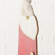 Nahaufnahme einer dekorativen Figur mit rotem Körper, weißem Bart und gestrickter Mütze, seitliche Perspektive.