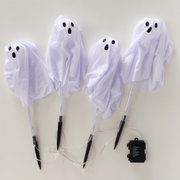 Vier weiße Halloween-Geisterfiguren aus Stoff mit schwarzen Augen und Mund auf transparenten Stäben, verbunden mit Kabeln und einem schwarzen Batteriekasten, Draufsicht auf hellem Hintergrund