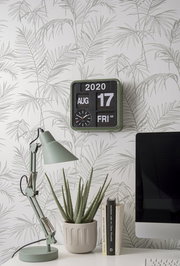 Wanduhr Mini in einem modernen Raum mit Pflanzenmotiv-Tapete, Schreibtischlampe und Computer, seitliche Perspektive