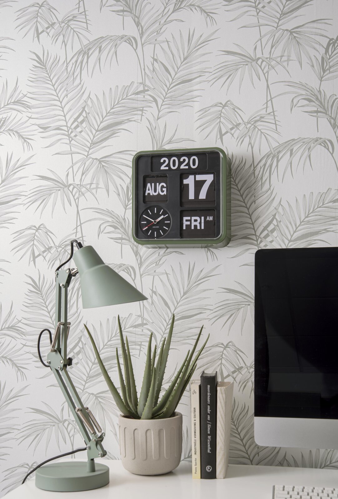 Mini-wandklok in een moderne kamer met behang met plantenmotief, bureaulamp en computer, zijaanzicht