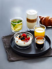 Espressoglas-Set mit 80ml Fassungsvermögen, präsentiert auf einem Tablett mit verschiedenen Getränken und einem Croissant, seitliche Perspektive.