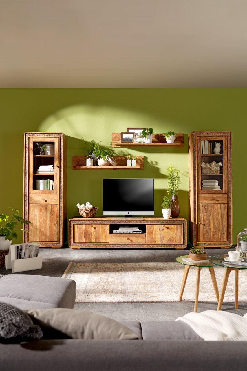 Wohnzimmermöbel-Set aus Holz mit TV-Tisch, Vitrinen und Wandregalen, frontal fotografiert vor einer grünen Wand.