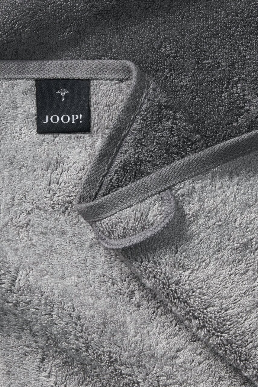 Grijze handdoek van JOOP! in close-up, met de zachte textuur en het label, gezien van bovenaf.