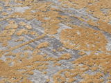 Nahaufnahme eines Designer-Teppichs mit goldenen und grauen Mustern in einer strukturierten Oberfläche, aus der Vogelperspektive betrachtet.