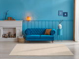 Beige Wollteppich in einem stilvoll eingerichteten Wohnzimmer mit blauer Wand, blauem Sofa und Kamin, aus der Vorderansicht fotografiert.