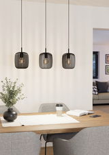 Drei moderne, schwarze Pendelleuchten Romazzina hängen über einem Esstisch in einem stilvoll eingerichteten Raum. Perspektive von vorne.