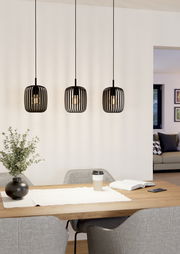 Drei moderne, schwarze Pendelleuchten Romazzina hängen über einem Esstisch in einem stilvoll eingerichteten Raum. Perspektive von vorne.