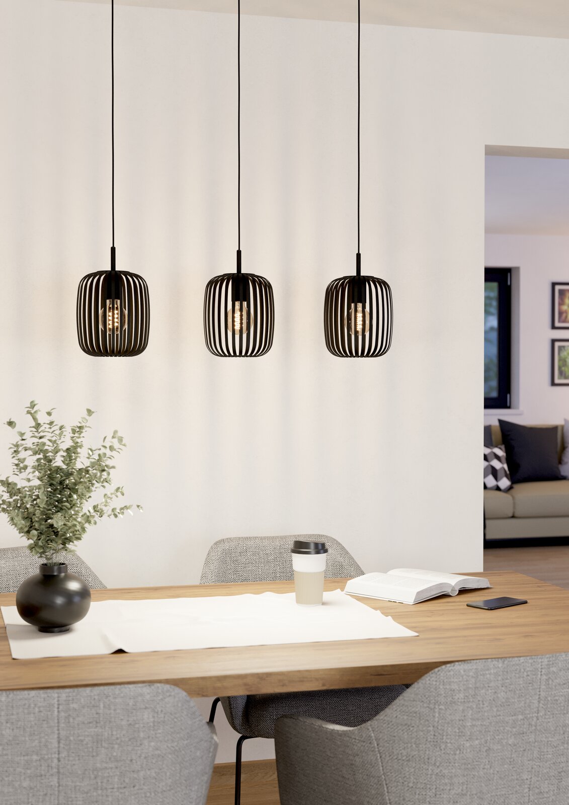 Drei moderne, schwarze Pendelleuchten Romazzina hängen über einem Esstisch in einem stilvoll eingerichteten Raum. Perspektive von vorne.