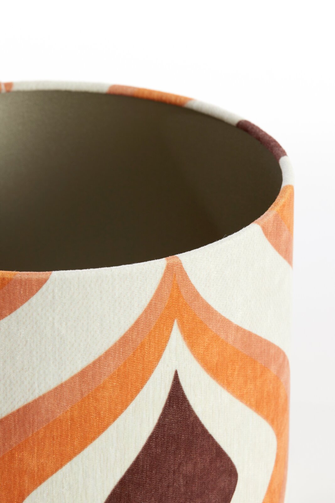 Close-up van een lampenkap met een kleurrijk, geometrisch patroon in oranje- en bruintinten, gezien van bovenaf.