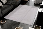 Fellteppich in einem modernen Wohnzimmer, aus der Vogelperspektive fotografiert, mit einem grauen Sofa und dekorativen Kissen im Hintergrund.