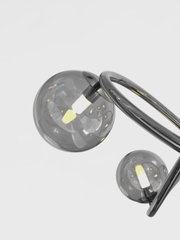 Moderne Pendelleuchte Nancy mit zwei rauchgrauen Glaskugeln und geschwungenem Metallrahmen, seitliche Perspektive